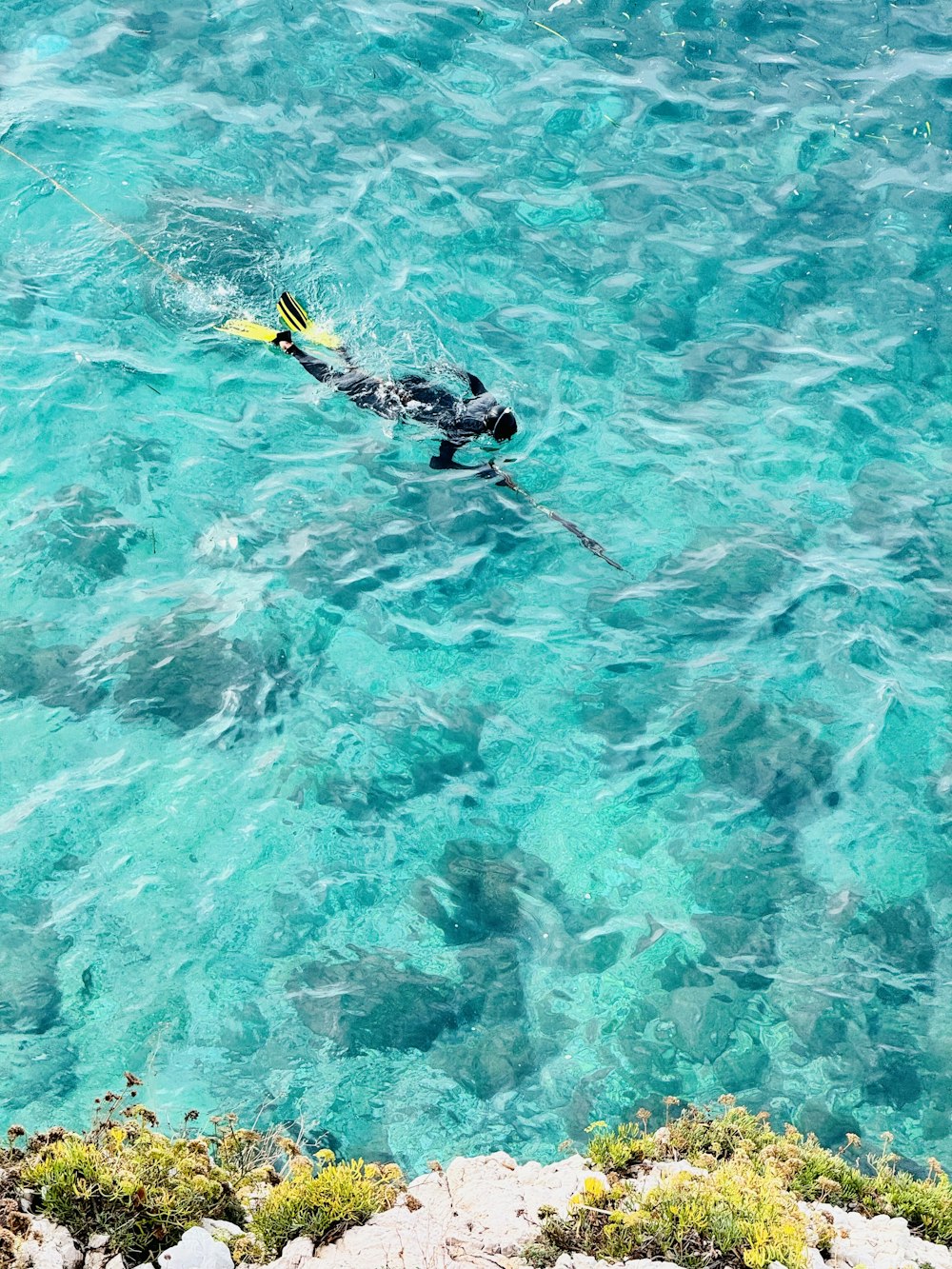 a person in a wet suit swimming in clear blue water