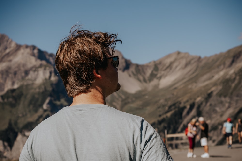 a man wearing sunglasses standing in front of a mountain range