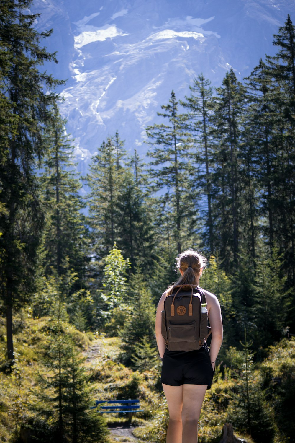 a woman with a backpack walking through a forest