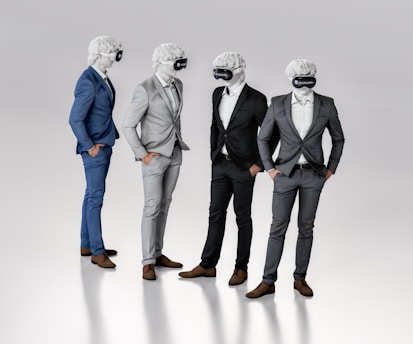 Four figures dressed in suits stand together, each wearing a virtual reality headset and featureless white masks resembling classical sculptures. They appear to be engaged in conversation or interaction, exhibiting a blend of classical and modern elements.