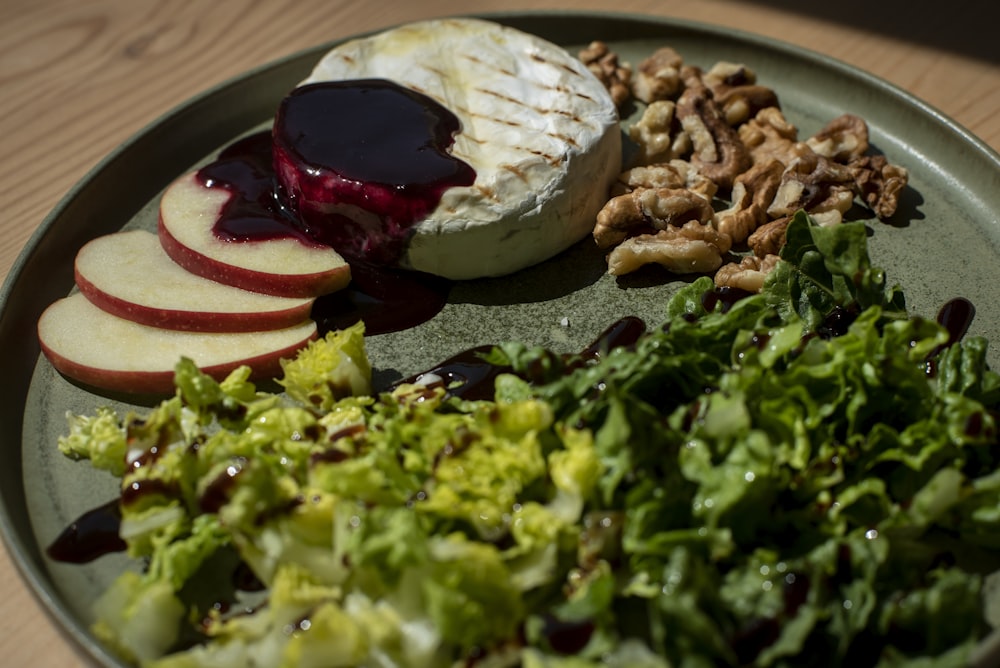 a plate of food that includes apples, salad and cheese