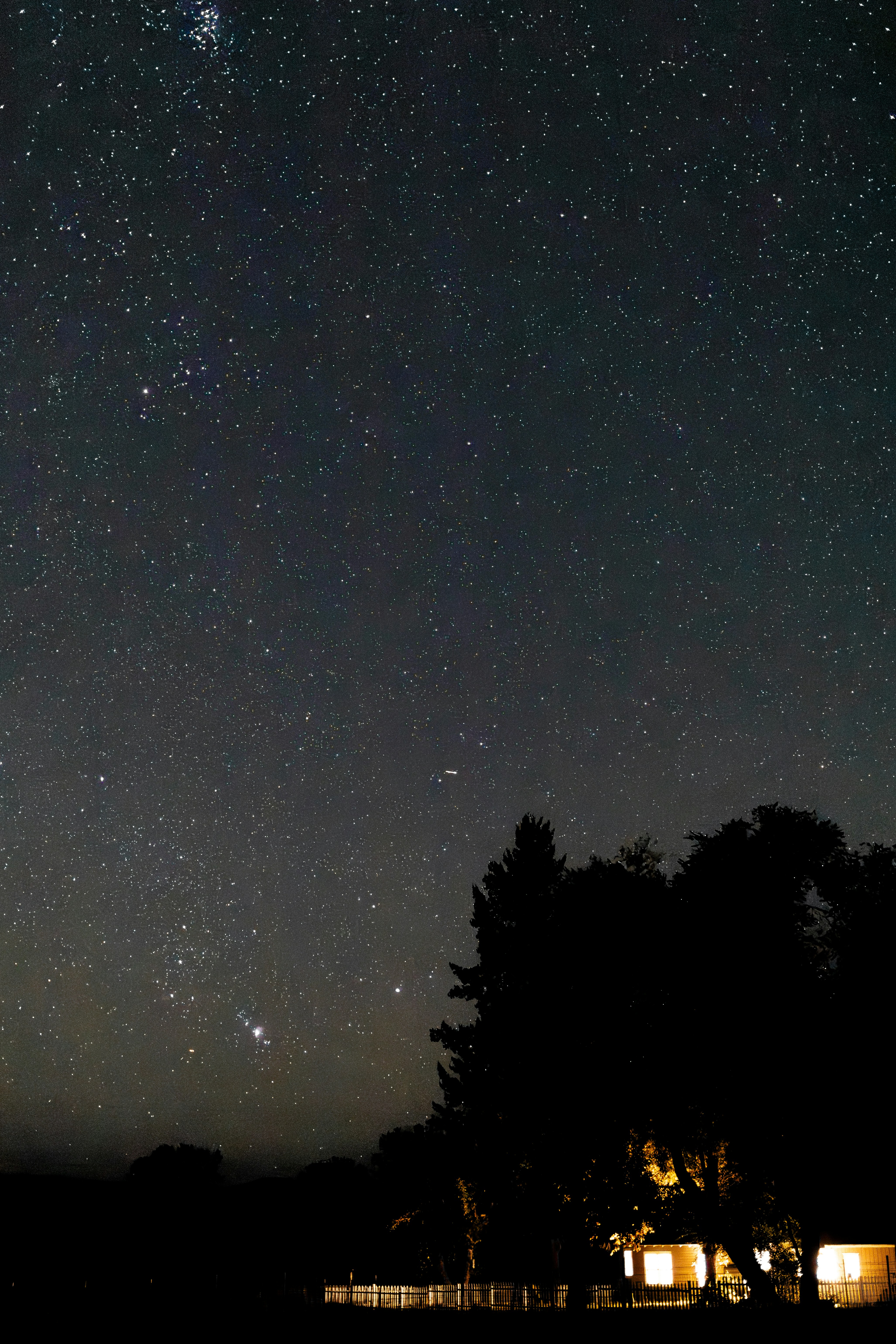 the night sky with stars above a house