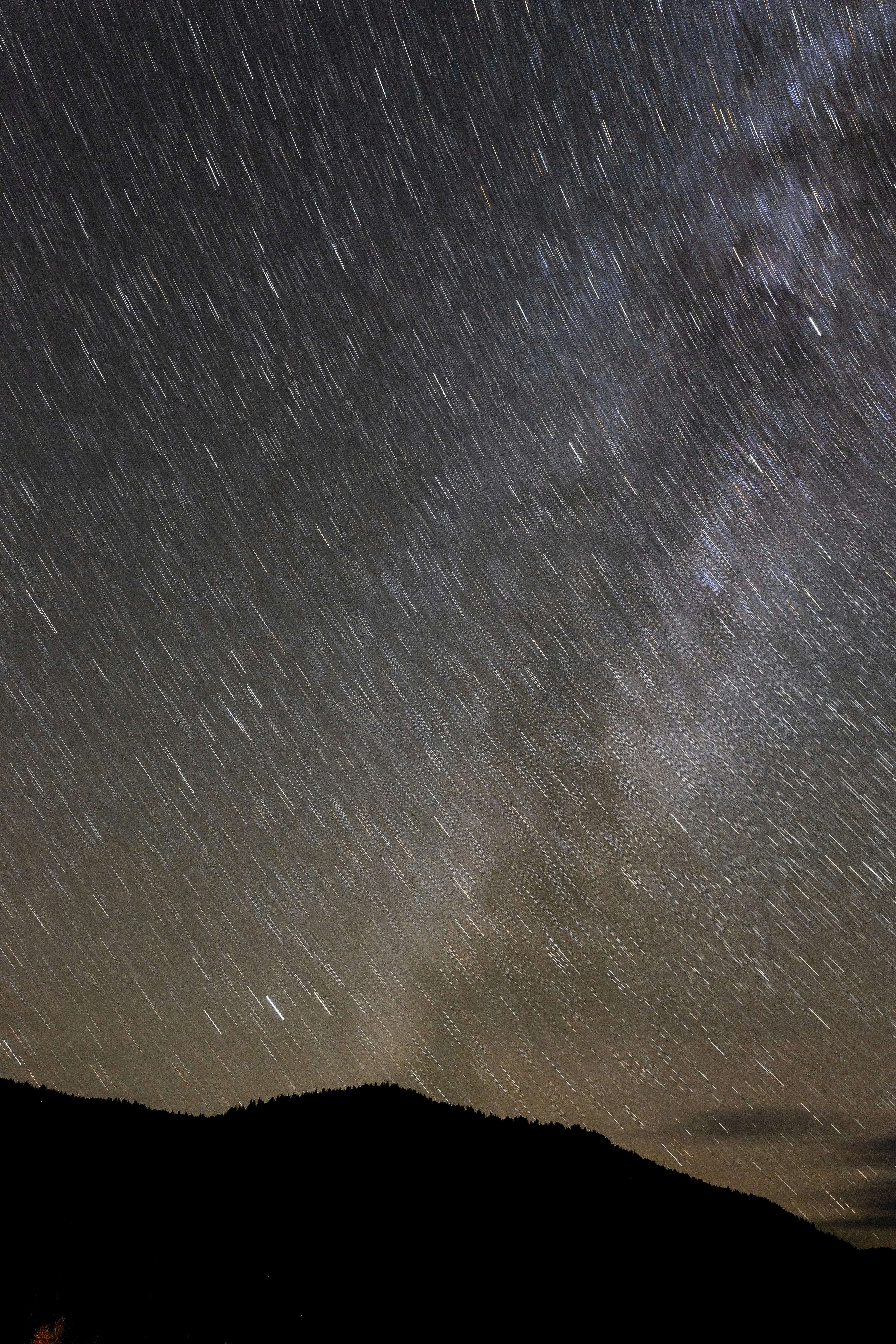 the night sky is filled with stars above a hill