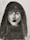 A monochrome charcoal portrait of a woman with long hair and bangs. The shading highlights her facial features such as the eyes, nose, and lips, giving depth and intensity to the portrait.
