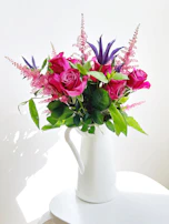 A cheerful ceramic pitcher filled with fresh flowers, glowing in natural light.