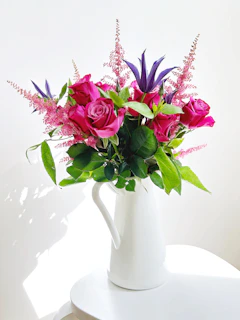 A cheerful ceramic pitcher filled with fresh flowers, glowing in natural light.