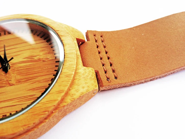 Close-up of a sleek, affordable men's watch with a leather strap resting on a wooden table.