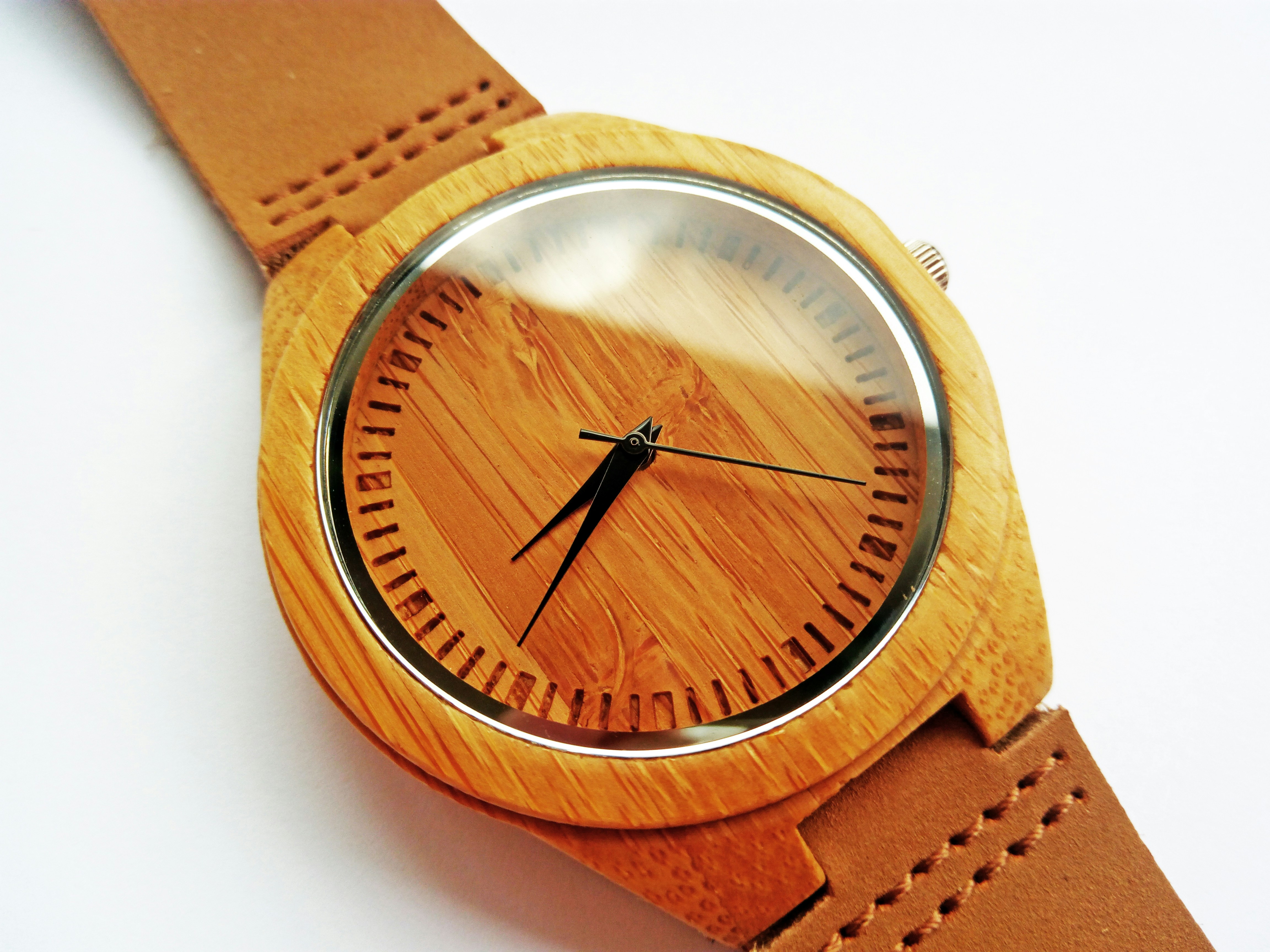 Bright white background with tan leather strap minimalist watch on clean surface, editorial