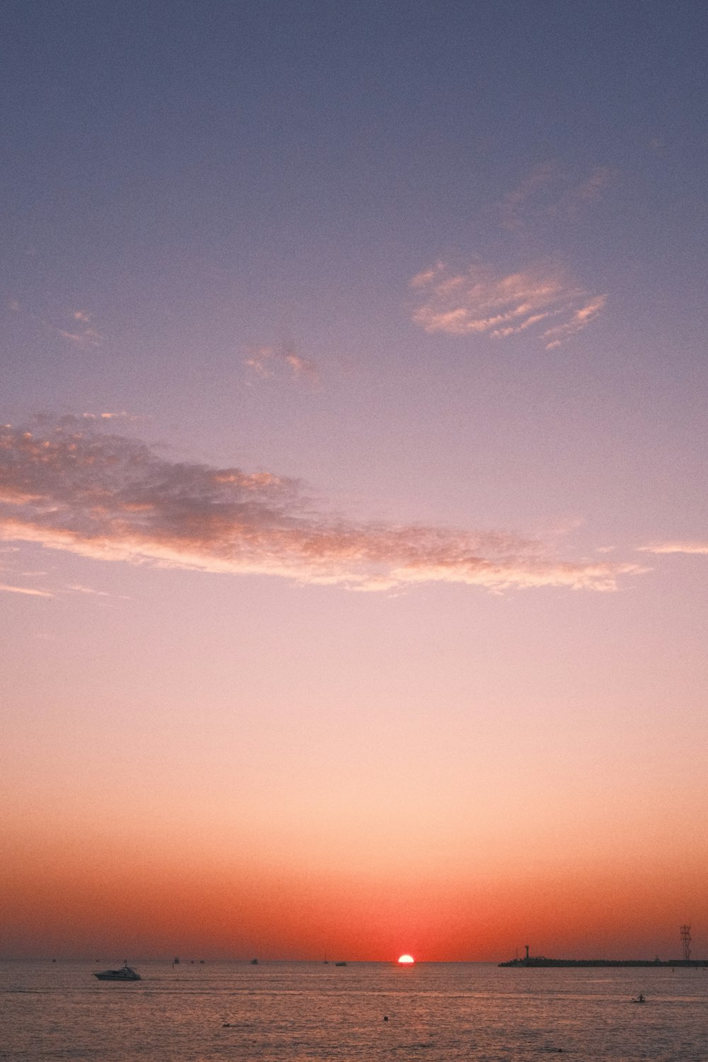 o sol está se pondo sobre o oceano com barcos na água