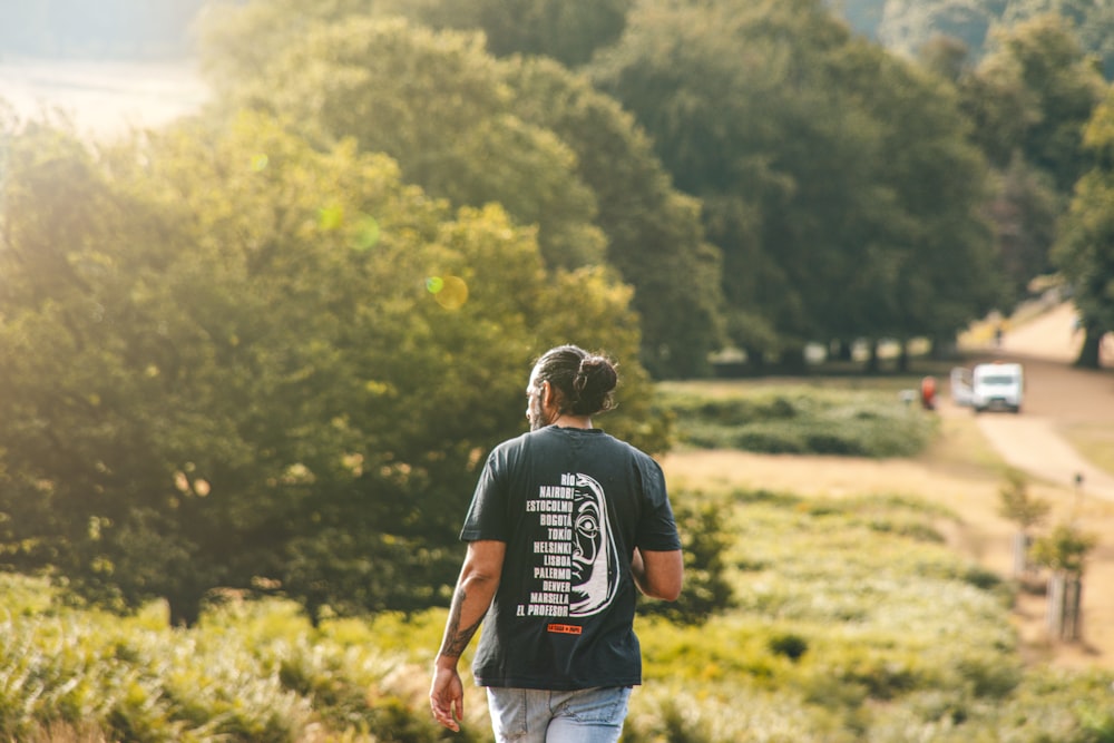 a man walking down a dirt road next to a forest