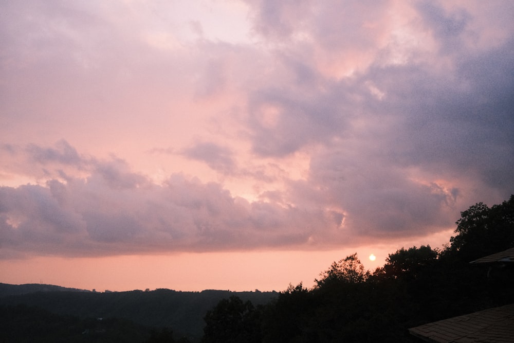 the sun is setting over the mountains and trees