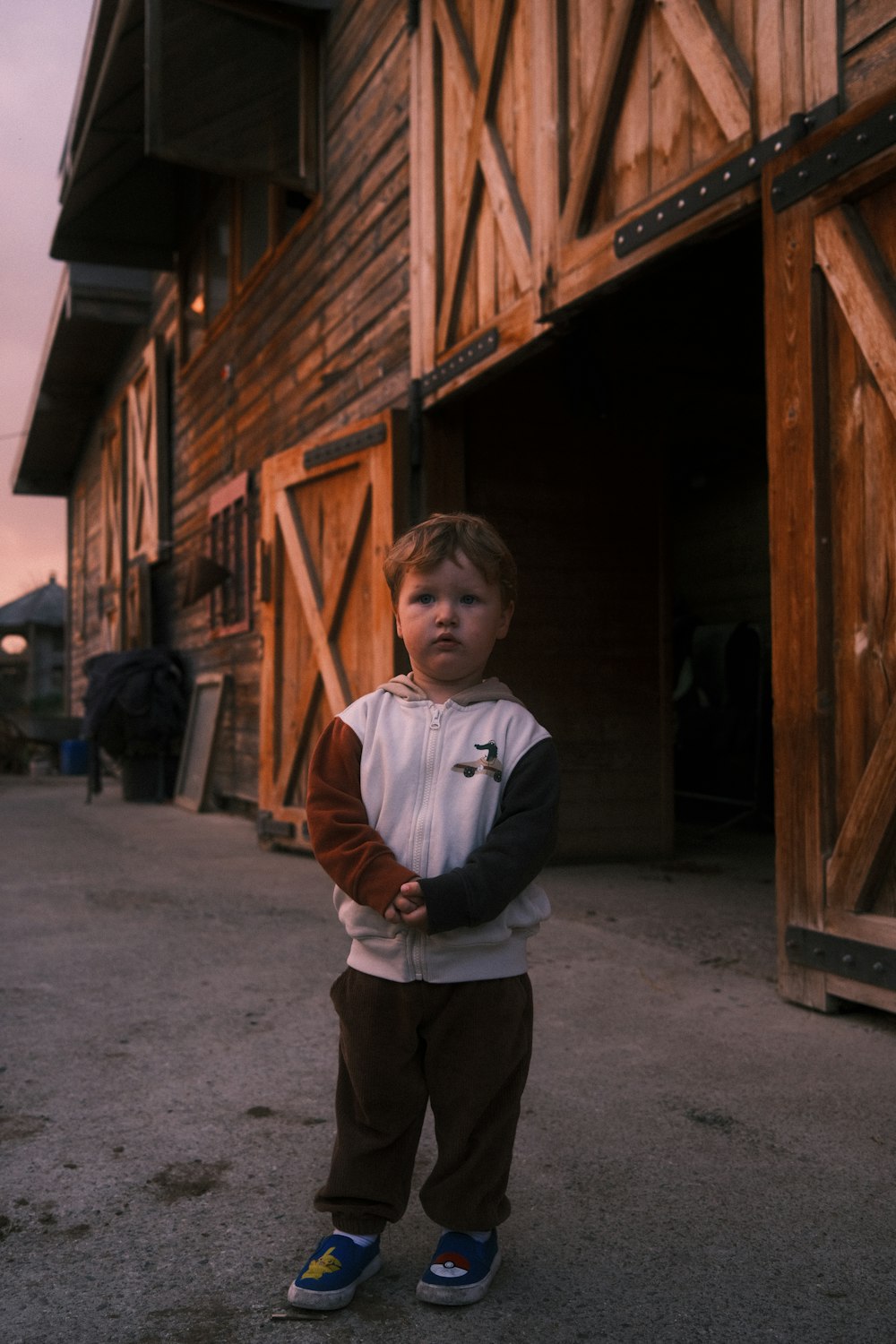 a young boy standing in front of a barn