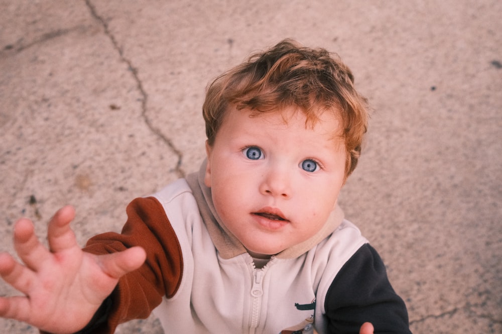 a little boy with blue eyes is holding out his hand