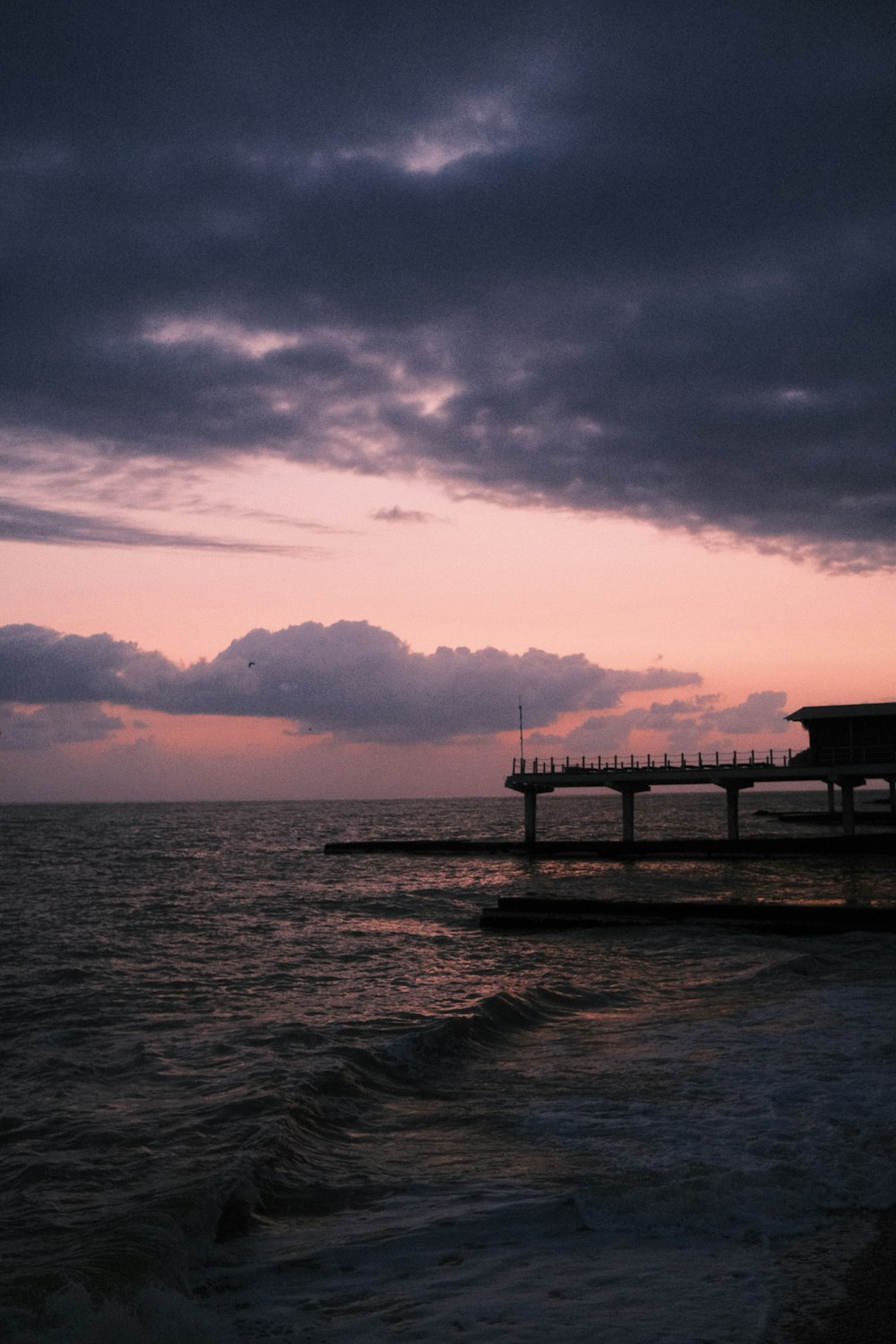 a pier sitting on top of a body of water under a cloudy sky