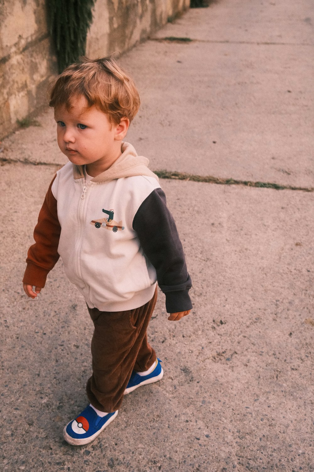 a little boy that is standing on a sidewalk
