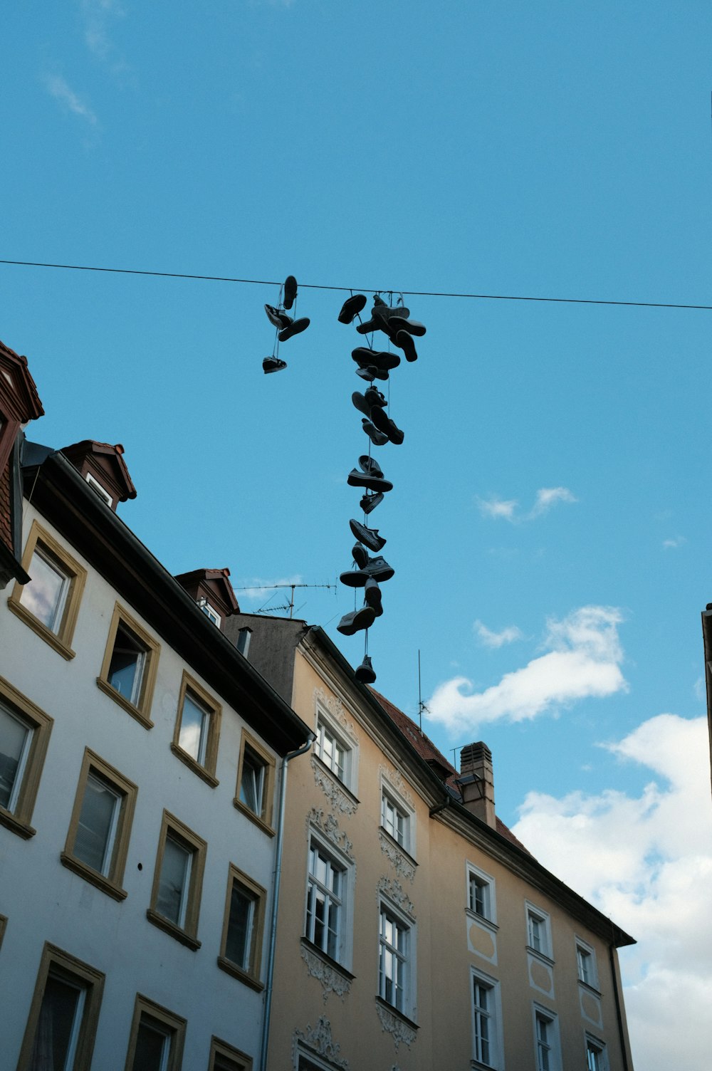 a bunch of shoes hanging from a wire in front of a building