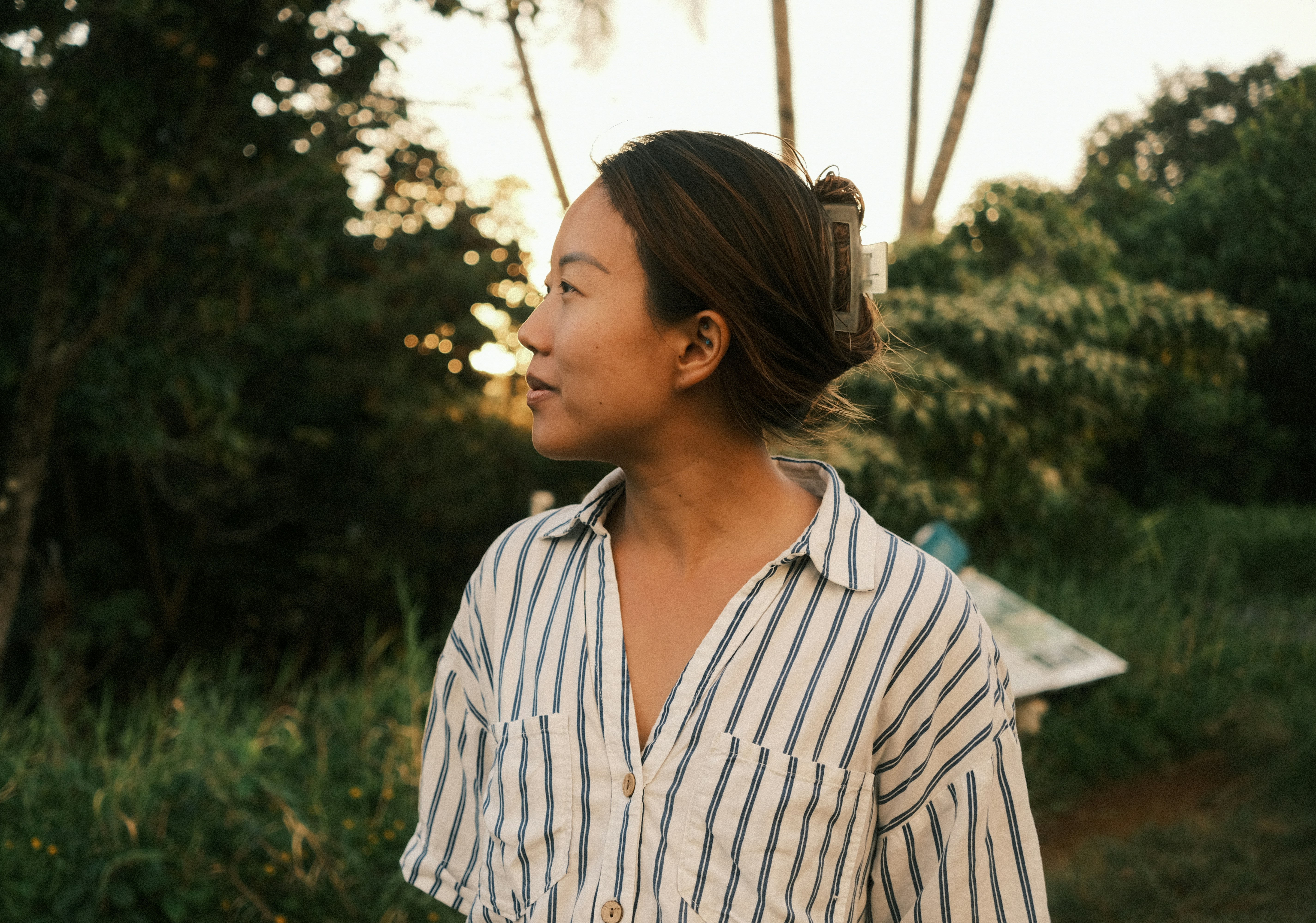 a woman standing in a field with trees in the background