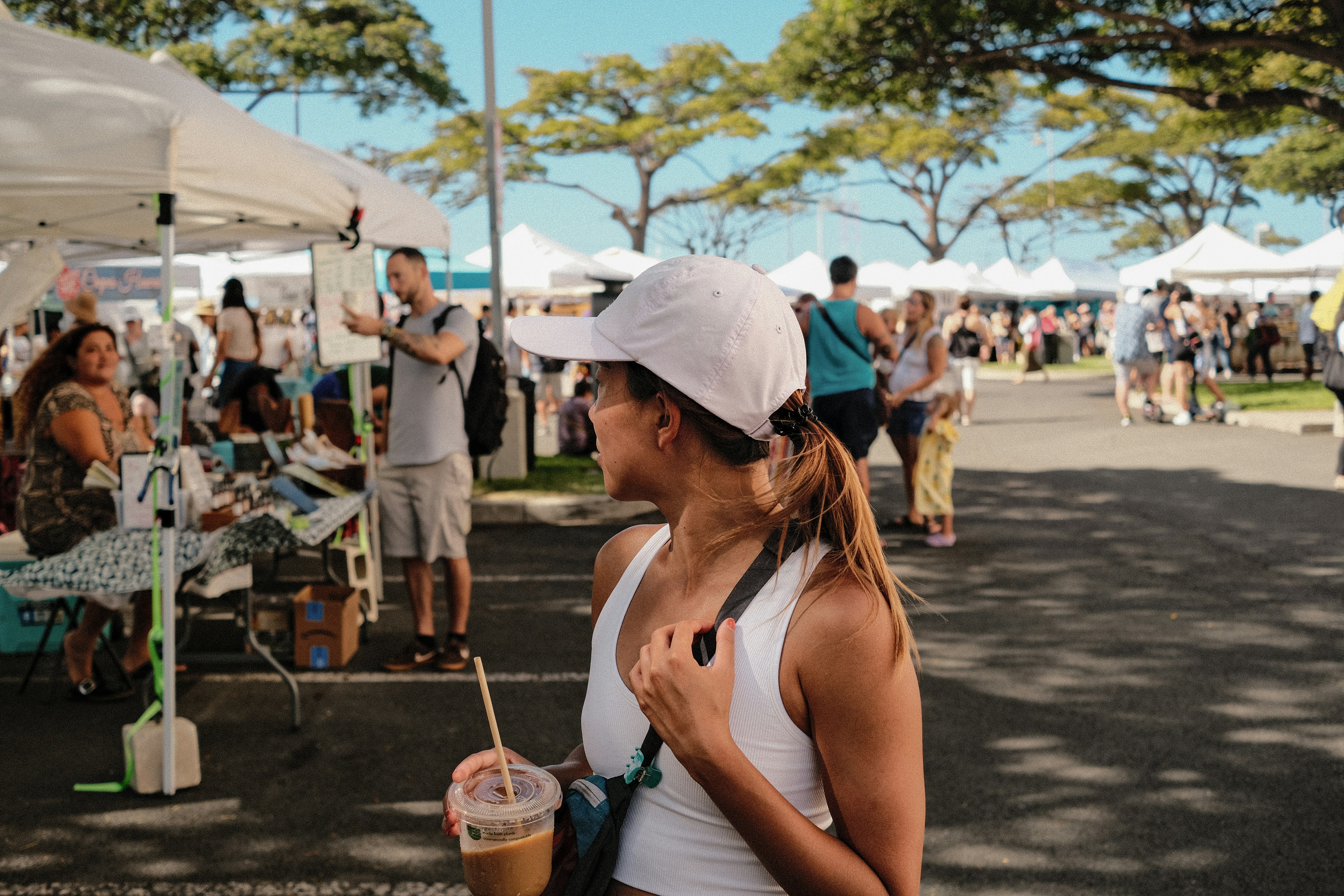 a woman in a white tank top holding a drink