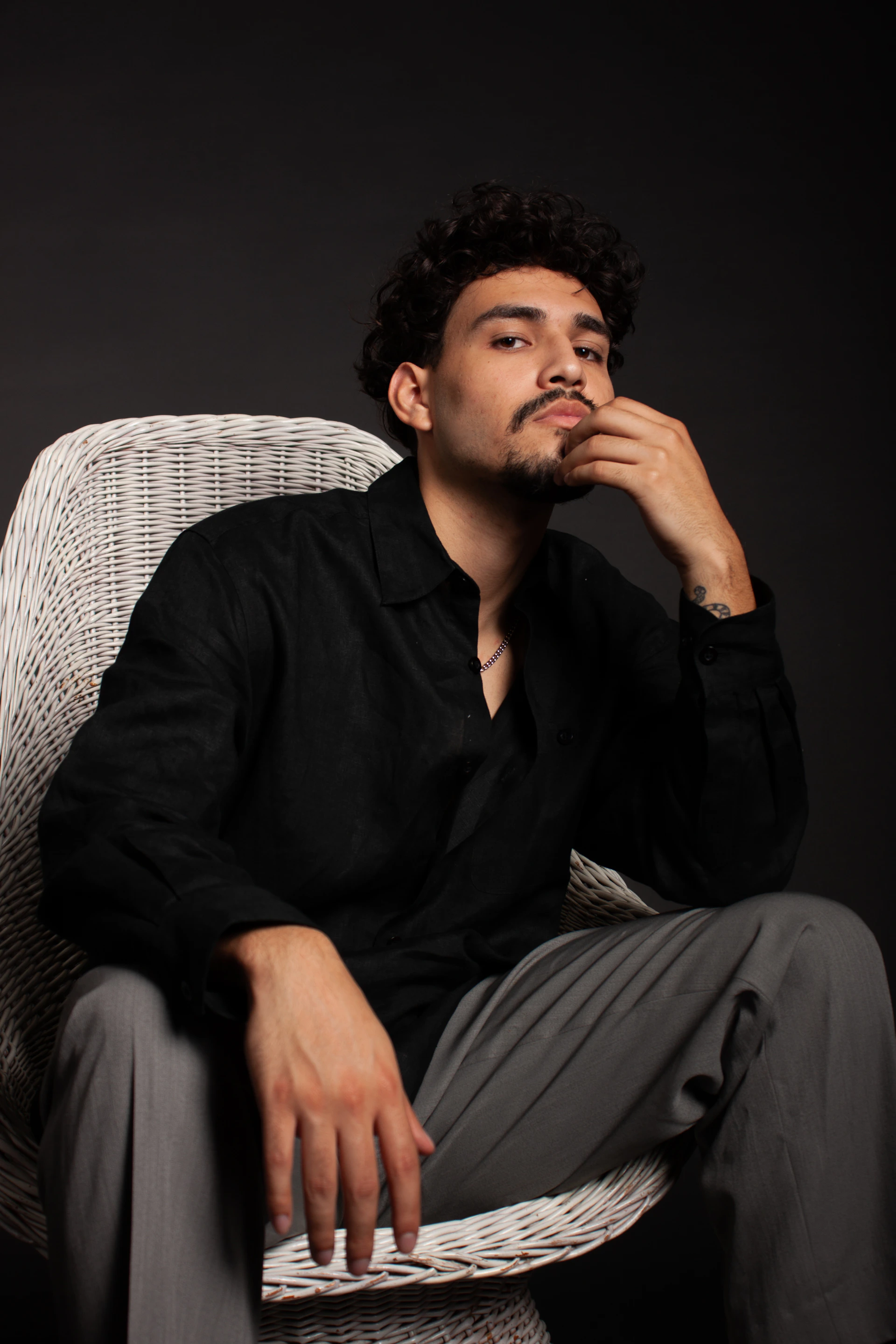 A man sitting in a chair with his hand on his chin