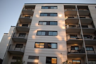 A newly finished residential complex with balconies and green spaces, bathed in warm sunlight.