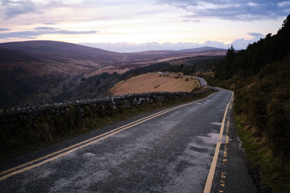 an empty road in the middle of a hilly area