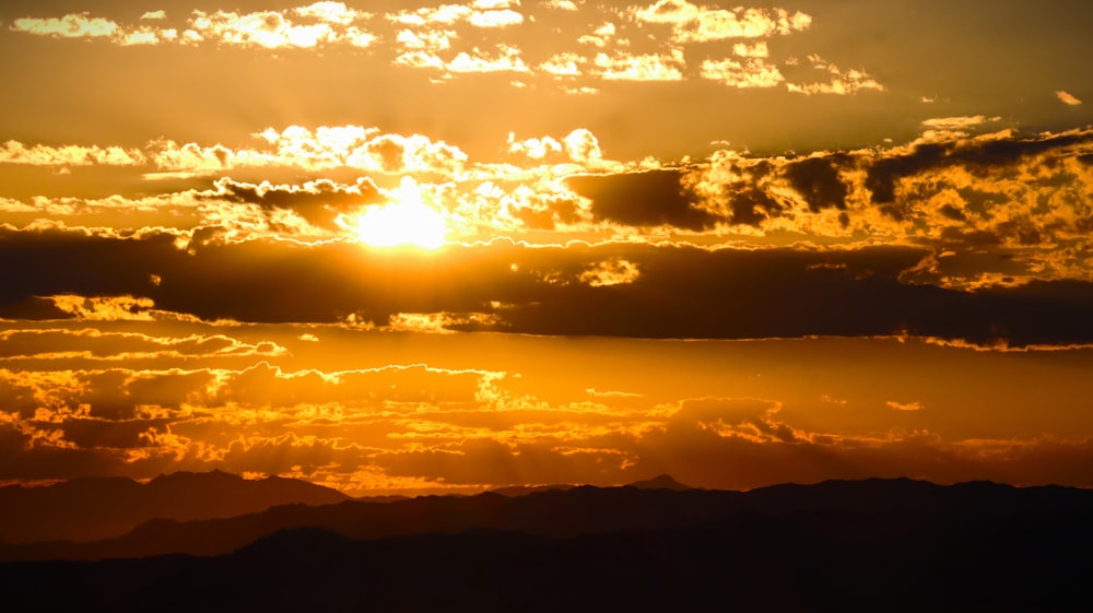 the sun is setting over a mountain range