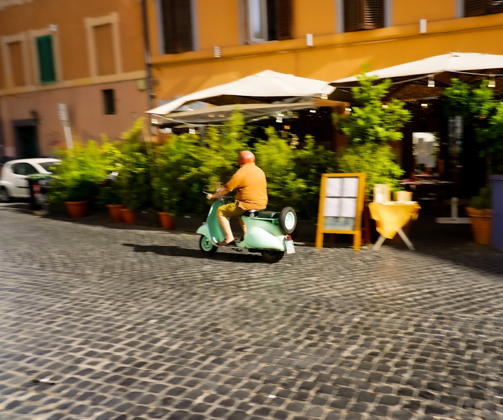 a man riding a scooter down a cobblestone street
