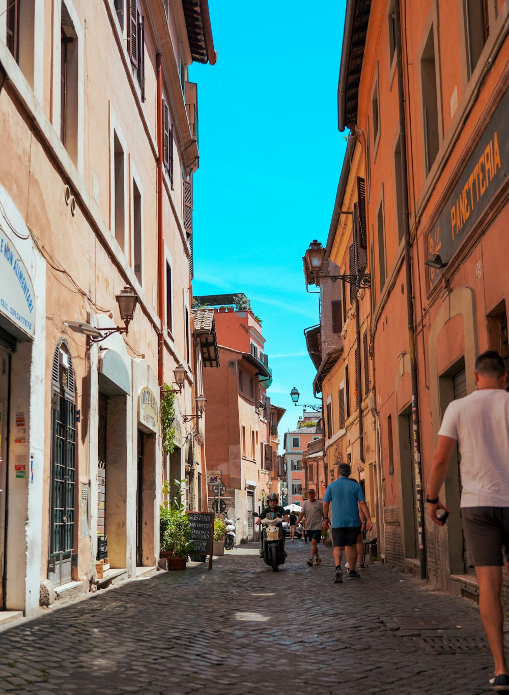 a group of people walking down a street next to tall buildings