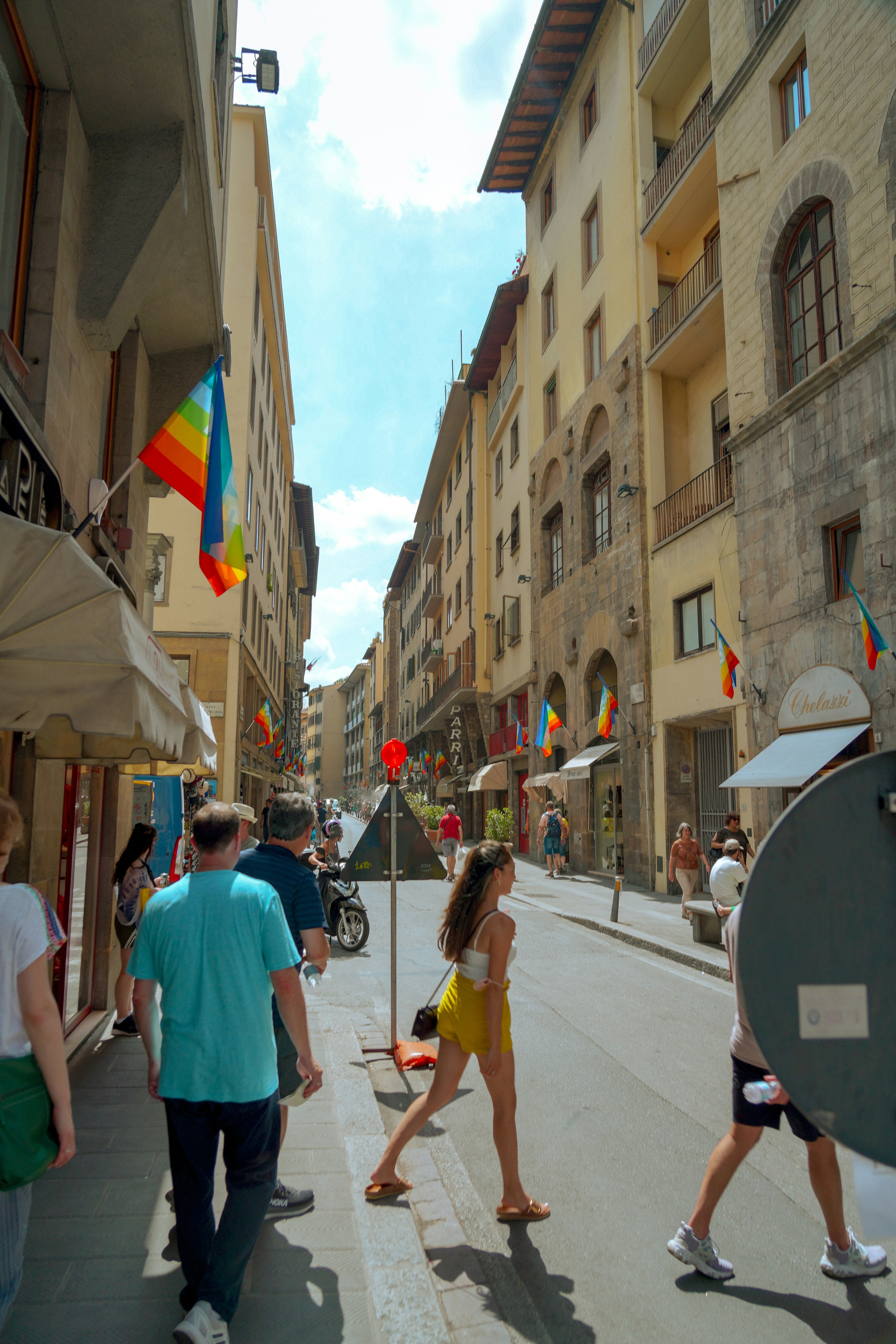 a group of people walking down a street next to tall buildings
