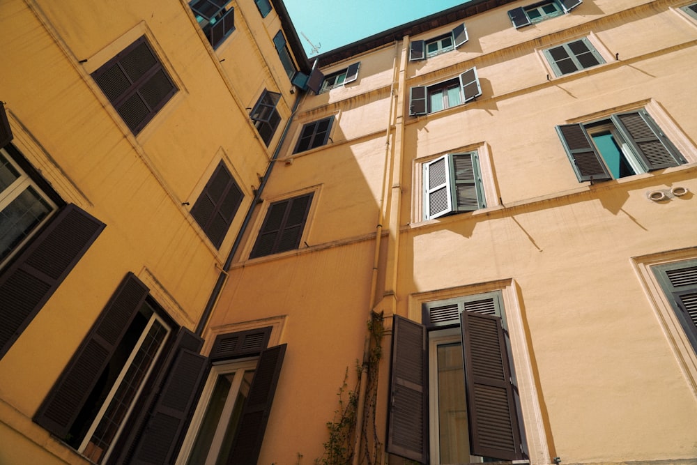 a yellow building with black shutters and windows