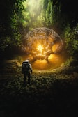 a man standing in front of a giant object in the middle of a forest