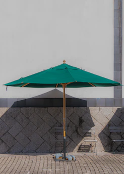 A sleek outdoor aluminum umbrella casting shade over a wooden patio table.