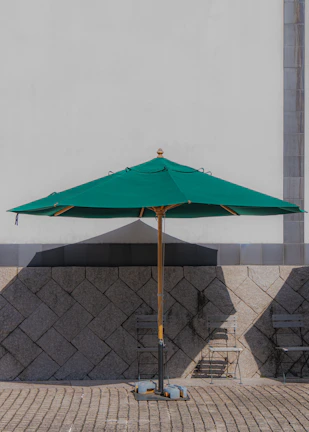 An outdoor aluminum umbrella casting shade over a rustic wooden grill table.