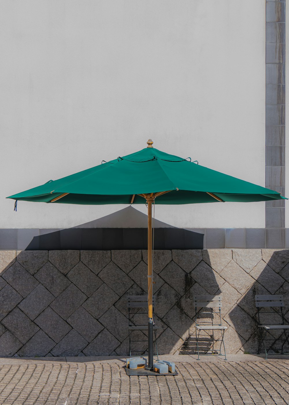 a green umbrella sitting on top of a sidewalk