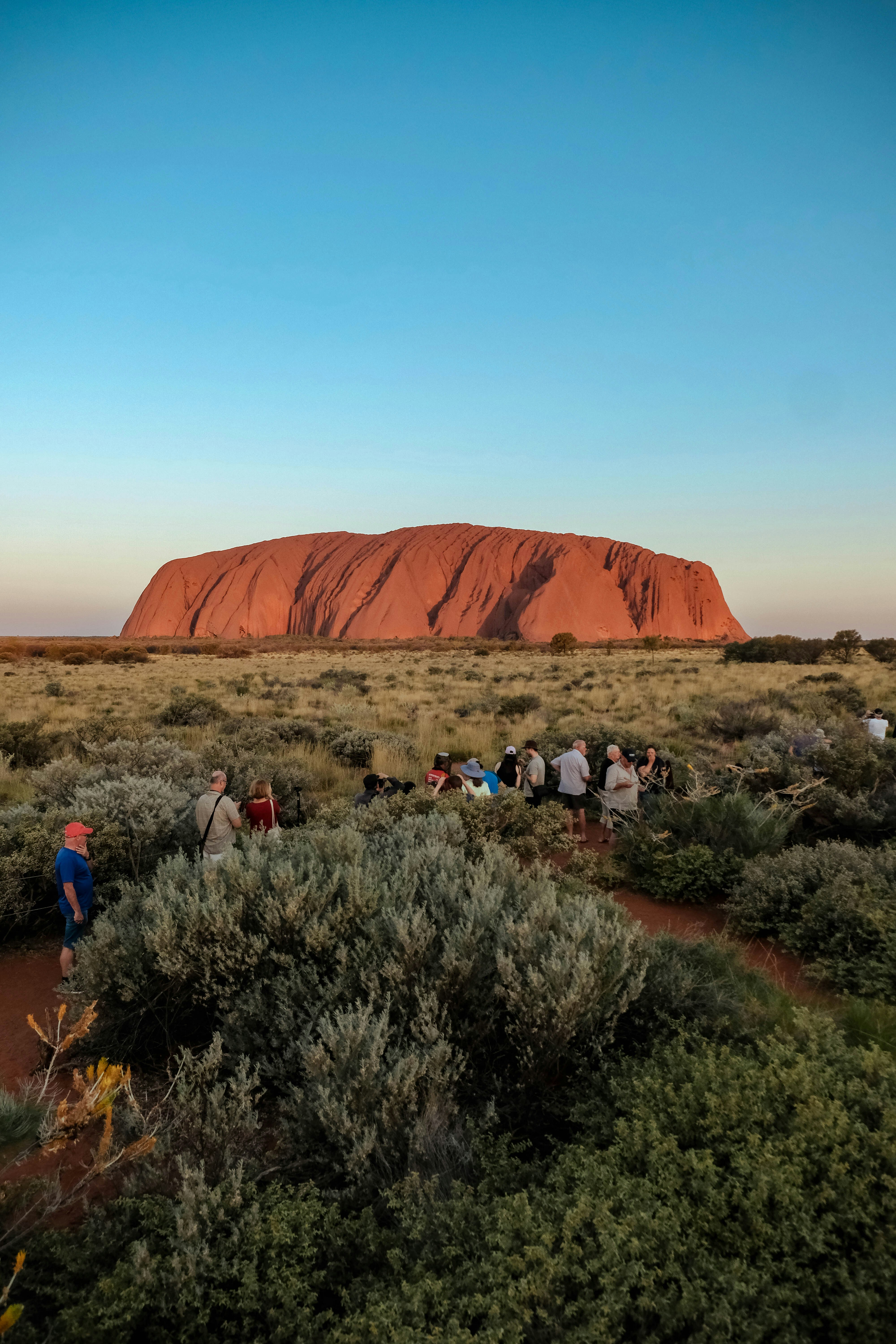 A group of people standing in front of a large rock photo – Free ...