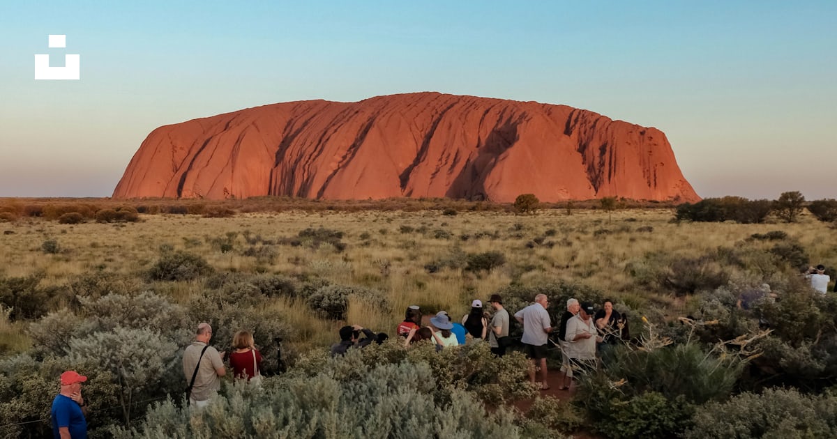 A group of people standing in front of a large rock photo – Free ...
