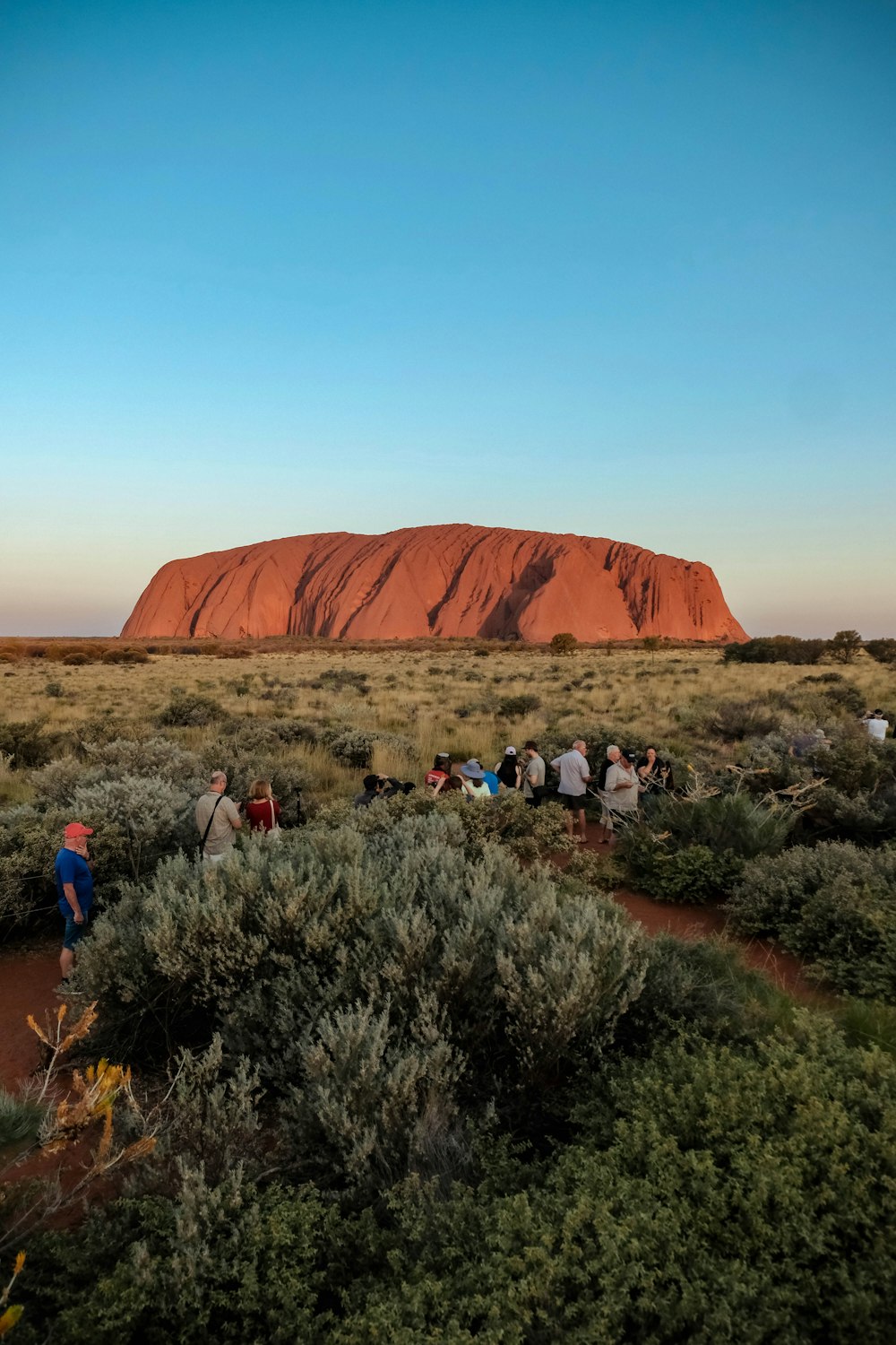 a group of people standing in front of a large rock