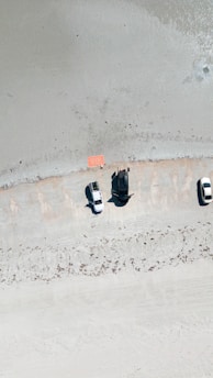 A bright sunny day showing a diverse range of vehicles parked near a sandy beach in Mayotte.