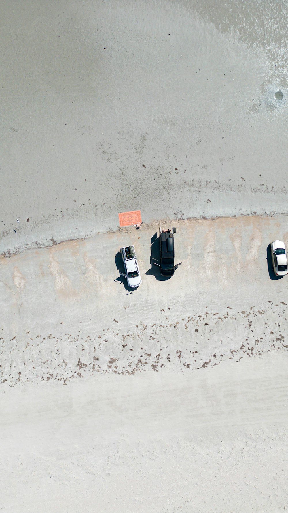 three cars parked on a beach near the ocean