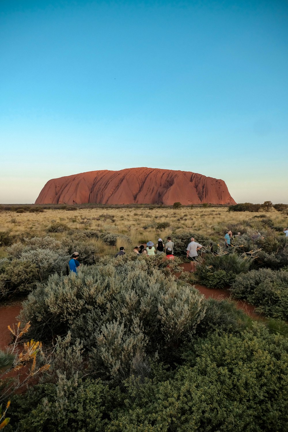 a group of people standing in front of a large rock