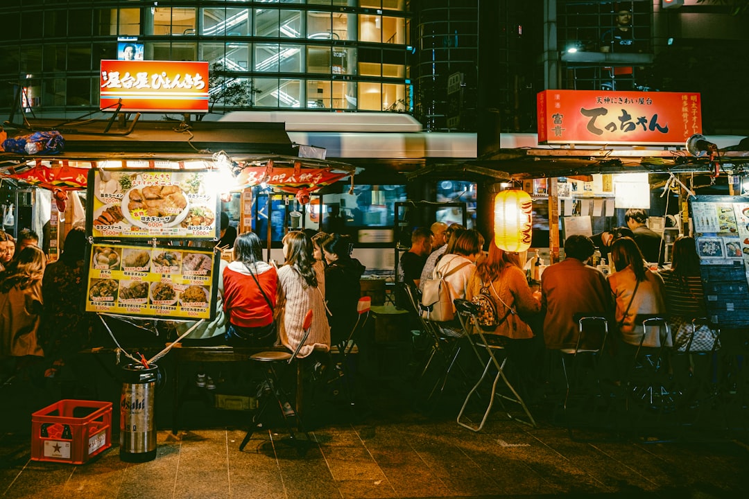 a group of people standing around a food stand,