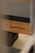 A close-up view of a Pilates reformer bearing the brand name 'bonPILATES'. The equipment is made of light-colored wood with a dark padded surface.