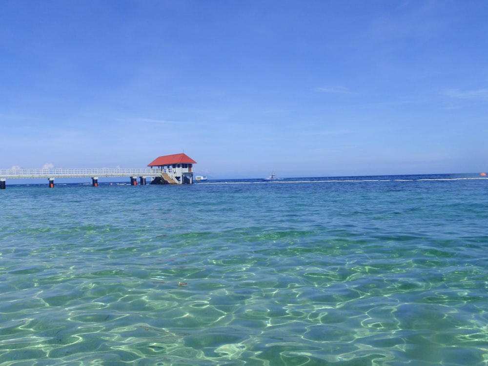 a red roofed house sitting on top of a body of water