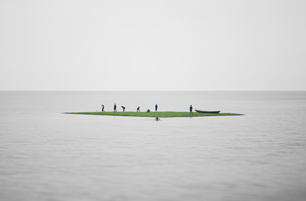 a group of people standing on a small island in the middle of the ocean