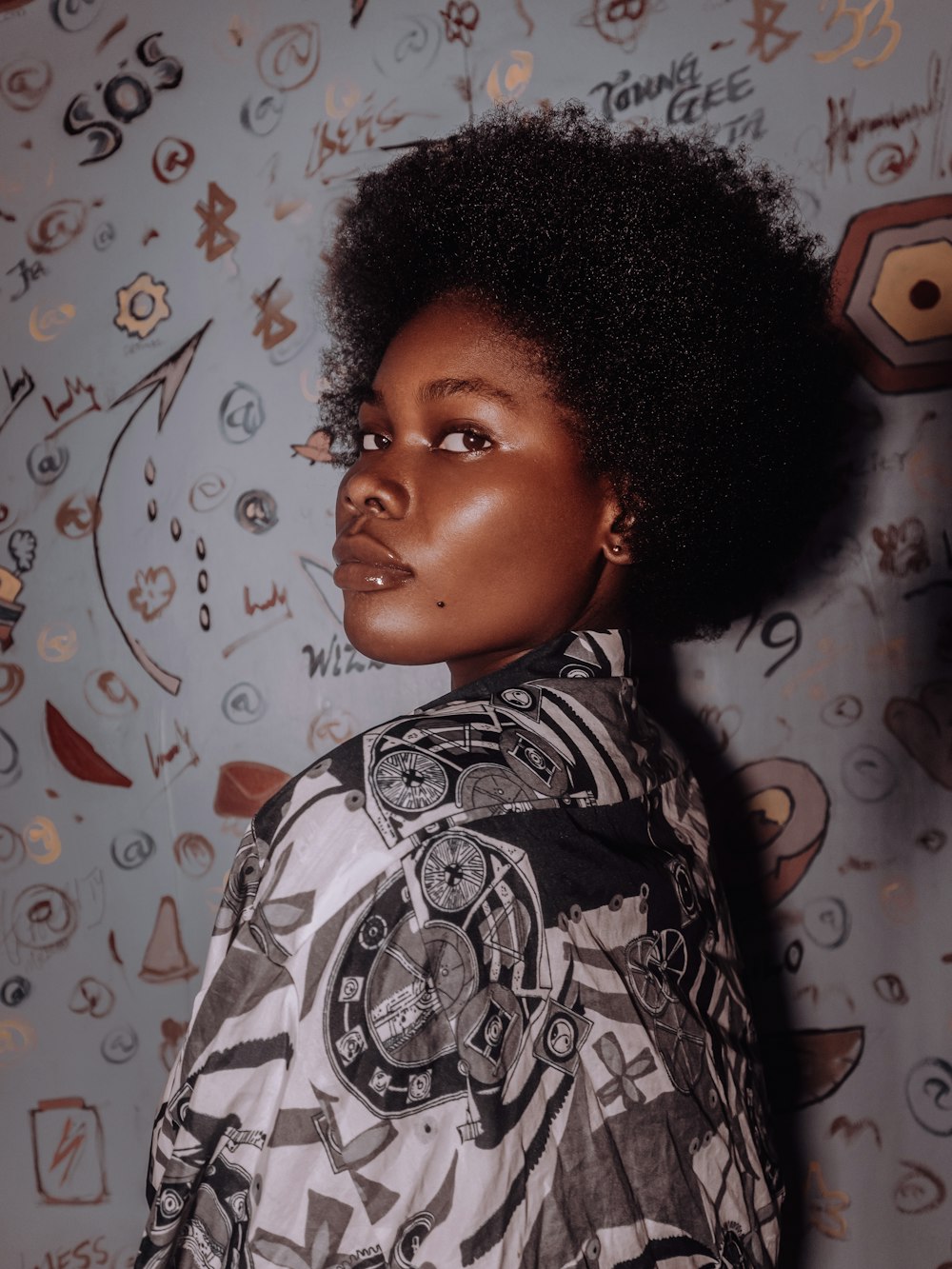 a woman with an afro standing in front of a wall