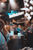 A friendly restaurant owner speaking on the phone with a backdrop of a busy kitchen.