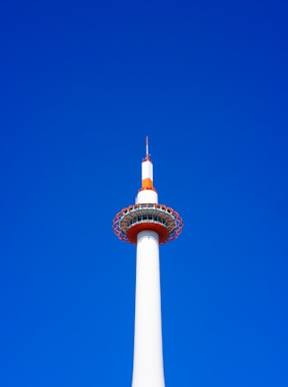 a tall white tower with a red top against a blue sky