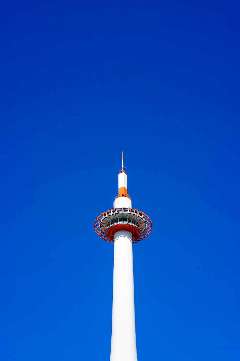 a tall white tower with a red top against a blue sky