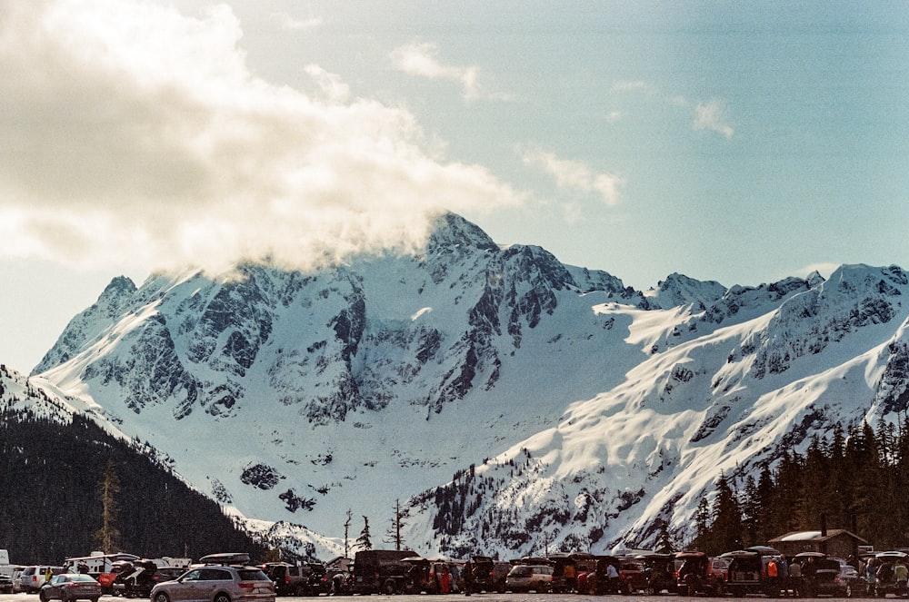 a snowy mountain range with cars parked in front of it