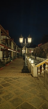 Evening scene of a quaint neighborhood street lit by vintage-style lamplighters.